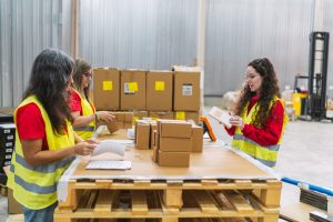 Female logistics workers scanning and preparing packages for delivery in a warehouse distribution center